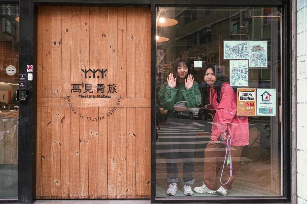 twee vrouwen die voor de deur van een winkel staan bij Meeting Mates Hostel in Taipei