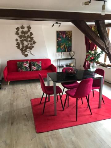 - un salon avec un canapé rouge, une table et des chaises dans l'établissement Les Dames au chapeau vert, à Saint-Omer