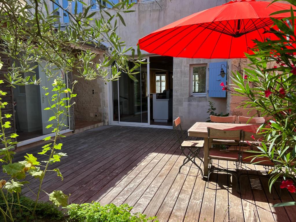 una terraza de madera con mesa y sombrilla roja en Maison de vacances BERENICE à St Martin de Ré, en Saint-Martin-de-Ré