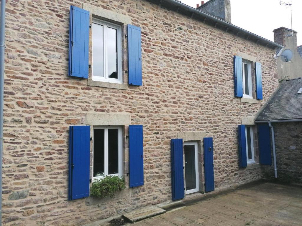 a brick building with blue shutters on it at Maison Kérity with Jacuzzi – Terrace in Paimpol