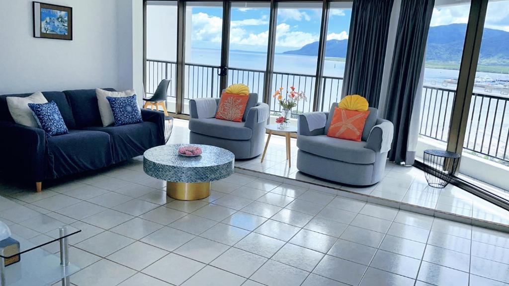 uma sala de estar com sofás, uma mesa e janelas em Cairns Ocean View Apartment in Aquarius em Cairns