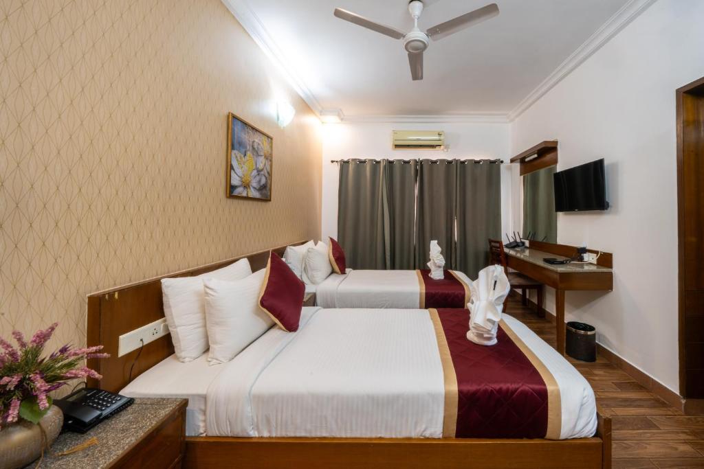 Habitación de hotel con 2 camas y escritorio en Midtown Suites Marathahalli Bangalore, en Bangalore