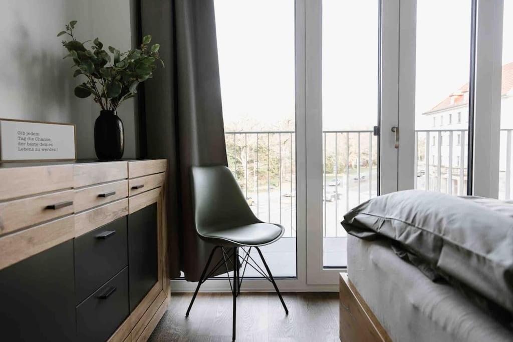 a bedroom with a chair next to a dresser and a bed at Gropius in Dessau