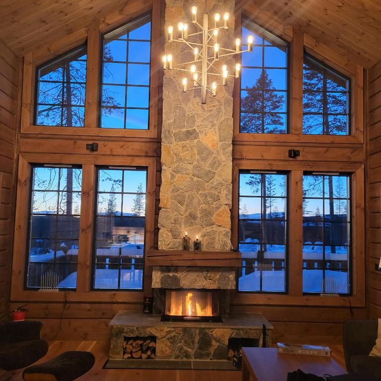 a living room with a stone fireplace and a chandelier at Idre Mountain Lodge with Sauna by Golf course in Idre