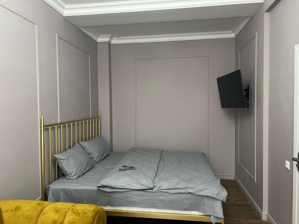 1 dormitorio con 1 cama y TV en la pared en Kadisheva - 3 en Qŭyliq