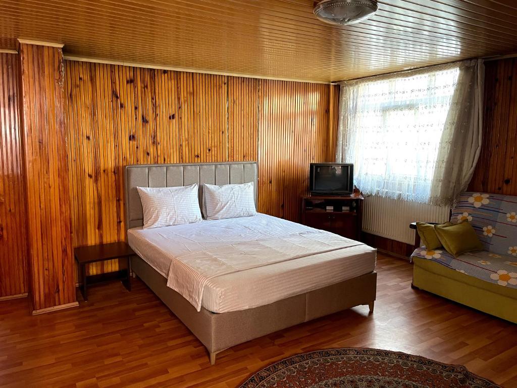 um quarto com uma cama, um sofá e uma televisão em KARAHANLAR Apart em Trebizonda