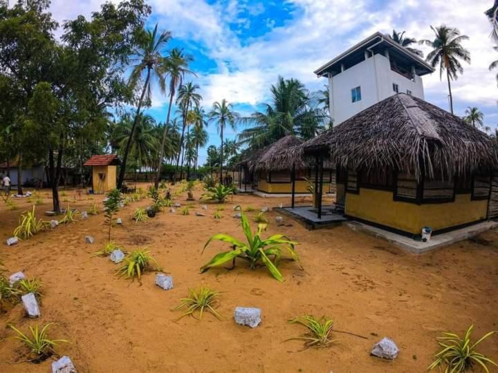 un pequeño edificio con techo de paja en una playa en LANKATHILAKA KITESURFING HOLIDAY RESORT, en Kalpitiya