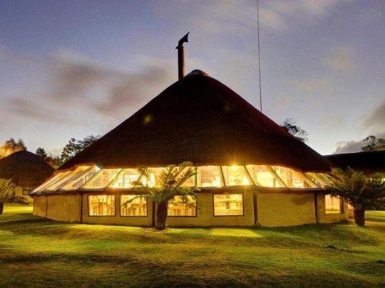 a large building with a pointed roof with lights at Hawane Resort in Mbabane