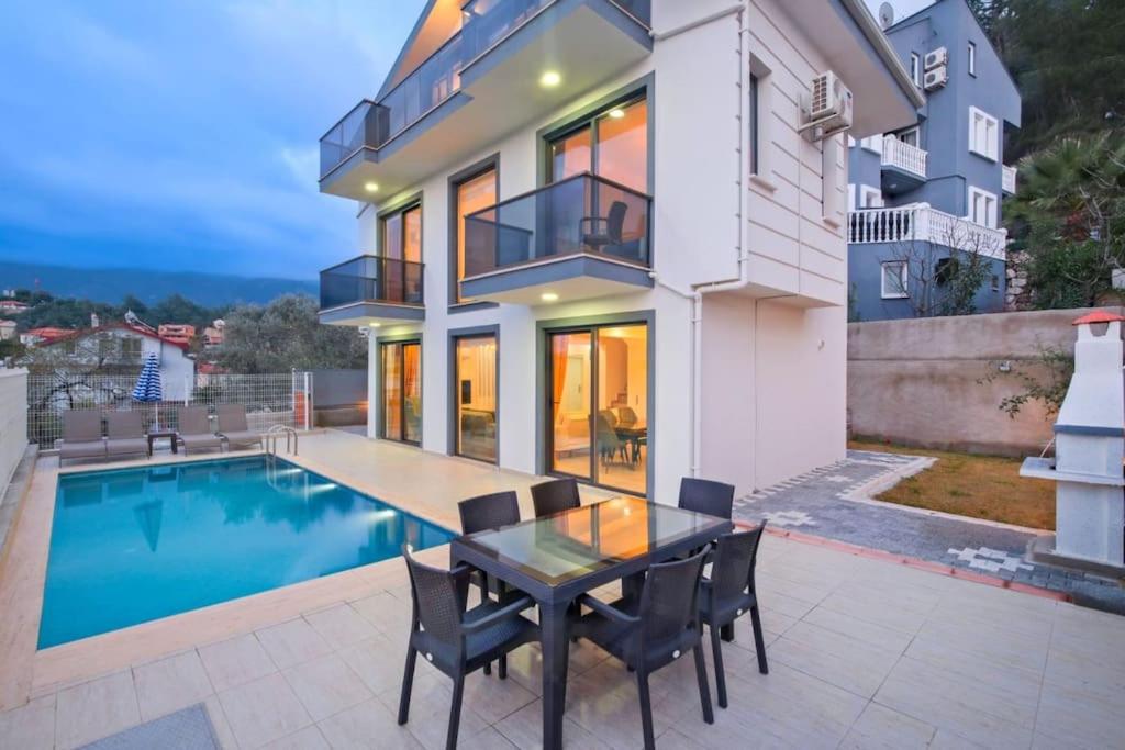 a house with a dining table and a swimming pool at Villa Simge 3+1 Ölüdeniz in Fethiye