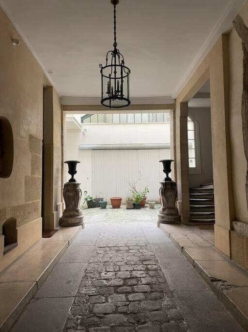un couloir vide avec un lustre dans un bâtiment dans l'établissement Charmant appart au cœur de Paris, à Paris
