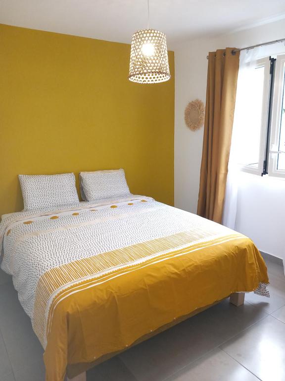 a bedroom with a large bed with a yellow wall at Ti kaz Salazie in Salazie