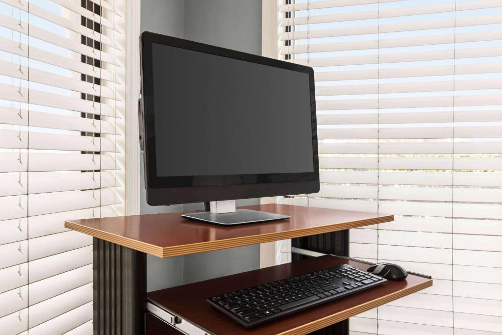 ein Computermonitor, eine Tastatur und eine Maus auf dem Schreibtisch in der Unterkunft Days Inn by Wyndham Cocoa Beach Port Canaveral in Cocoa Beach