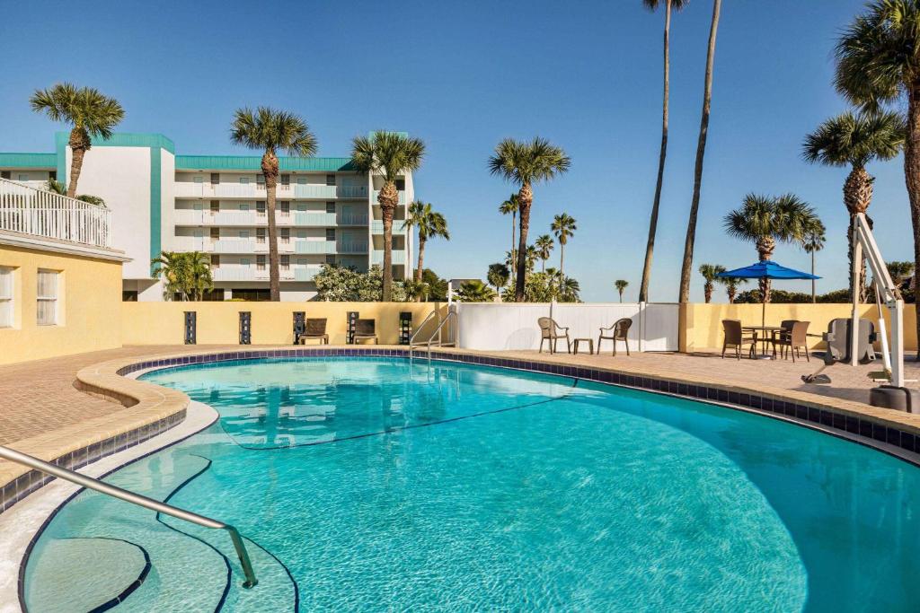 ein Swimmingpool in einem Resort mit Palmen in der Unterkunft Days Inn by Wyndham Cocoa Beach Port Canaveral in Cocoa Beach