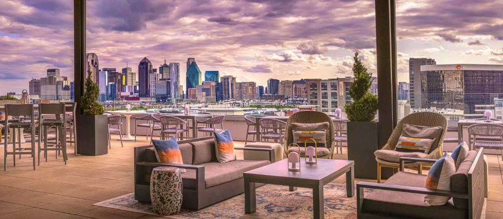 a rooftop patio with chairs and tables and a city skyline at Canopy By Hilton Dallas Uptown in Dallas