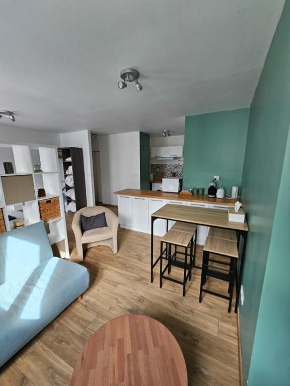 un salon avec une table et une cuisine dans l'établissement L'émeraude, à Auxerre