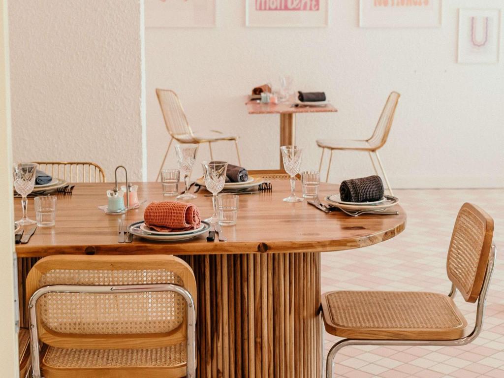 a wooden table with chairs and plates and glasses at greet hôtel Pont du Gard - Route d'Avignon in Estézargues