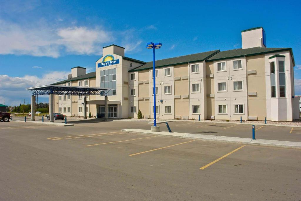 a large building with a parking lot in front of it at Days Inn by Wyndham Stony Plain in Stony Plain