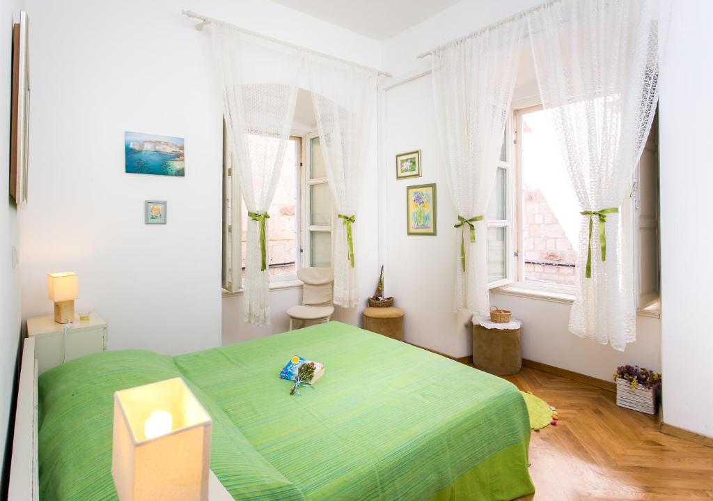 a bedroom with a bed with a green blanket at Apartments Adriana Flora in Dubrovnik