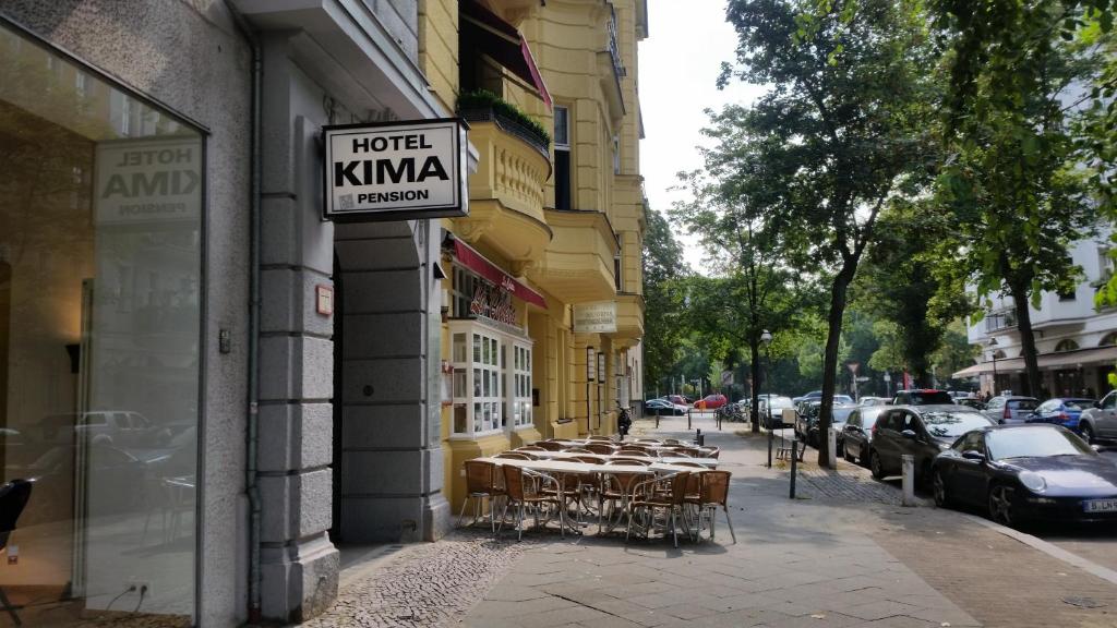 un gruppo di tavoli su un marciapiede accanto a un edificio di Hotel Pension Kima a Berlino