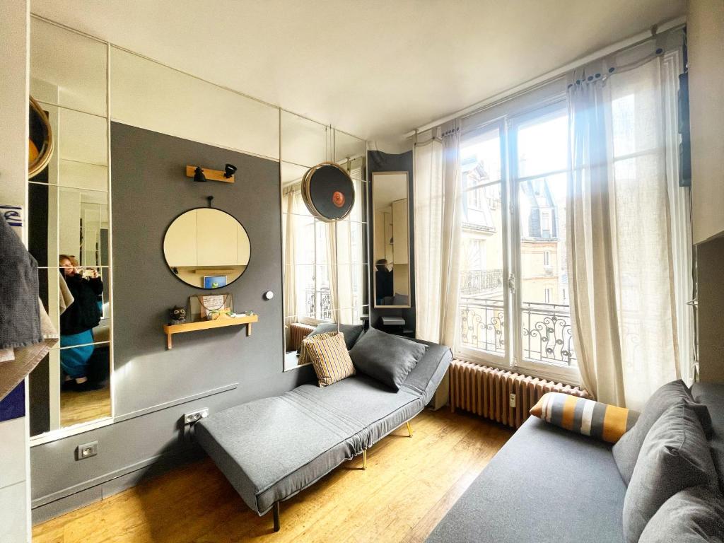 a living room with a couch and a large window at Quartier Latin Paris in Paris
