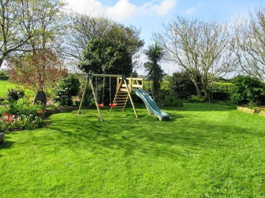 un parque infantil en un patio con césped verde en Maison dans son écrin de verdure, en Plouvien