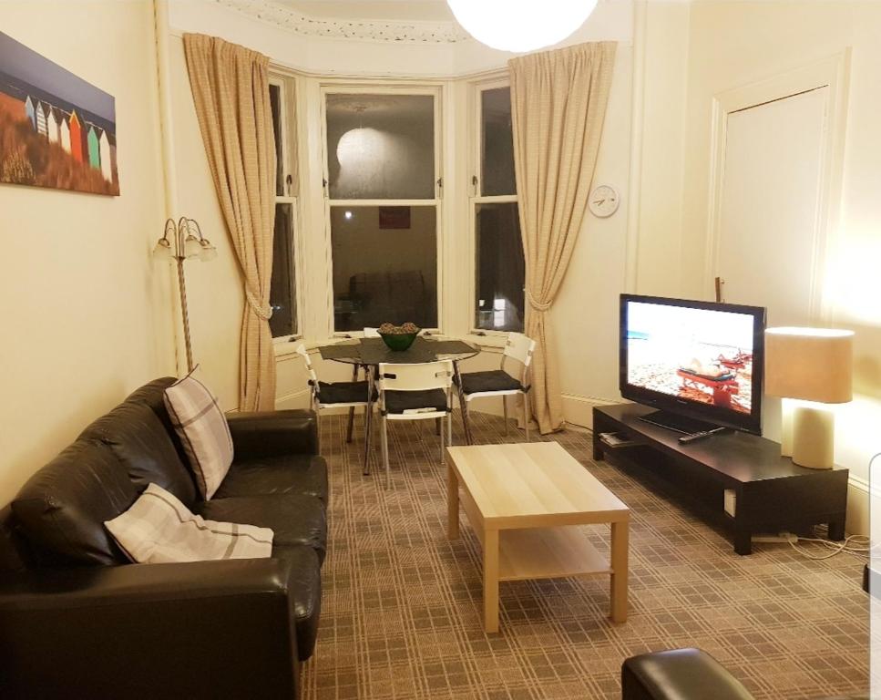 een woonkamer met een bank en een tafel met een televisie bij Glen Self-catering Apartment in Port Glasgow