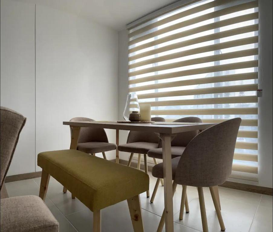 una sala da pranzo con tavolo, sedie e finestra di Apartamento nuevo Manizales. a Manizales