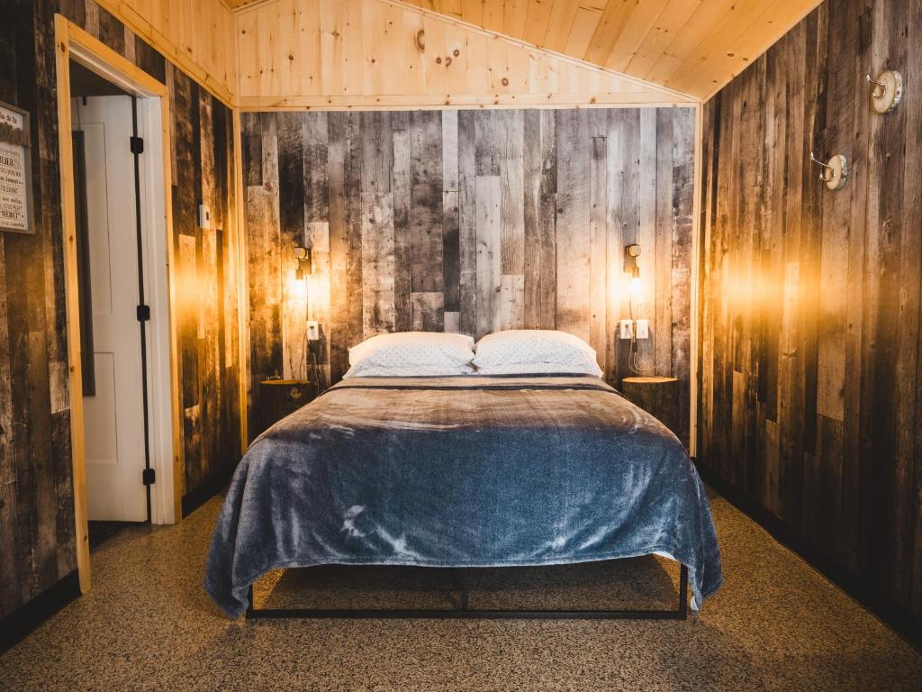 um quarto com uma cama e uma parede de madeira em Chalet - Abenaki Aventure em Pierreville