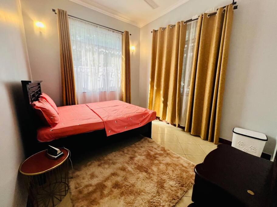 Mały pokój z czerwonym łóżkiem i oknem w obiekcie 1 Bedroom Apt - The Abode Mori w mieście Dar es Salaam