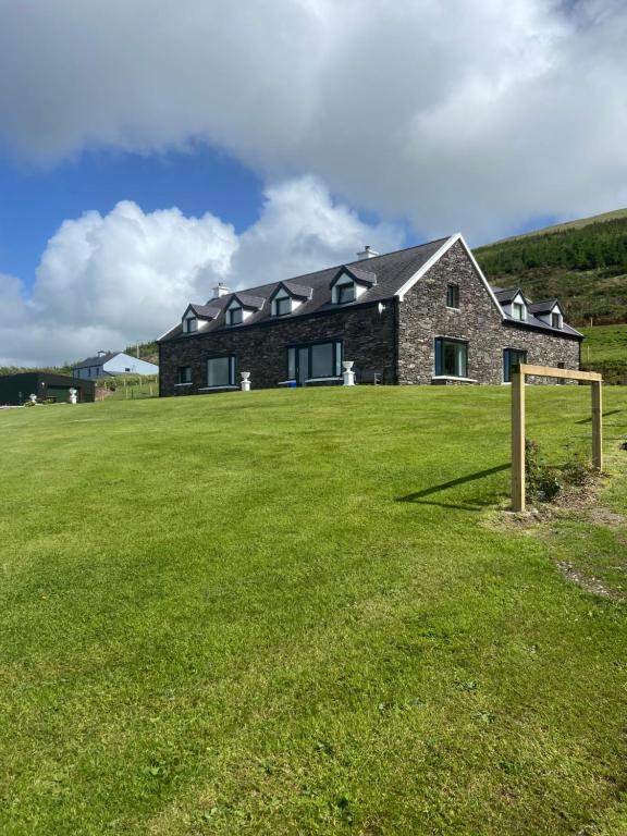 a house with a large grass field in front of it at Valentia View in Portmagee