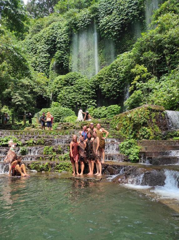 un grupo de personas de pie en el agua cerca de una cascada en Tastura Homestay, en Praya