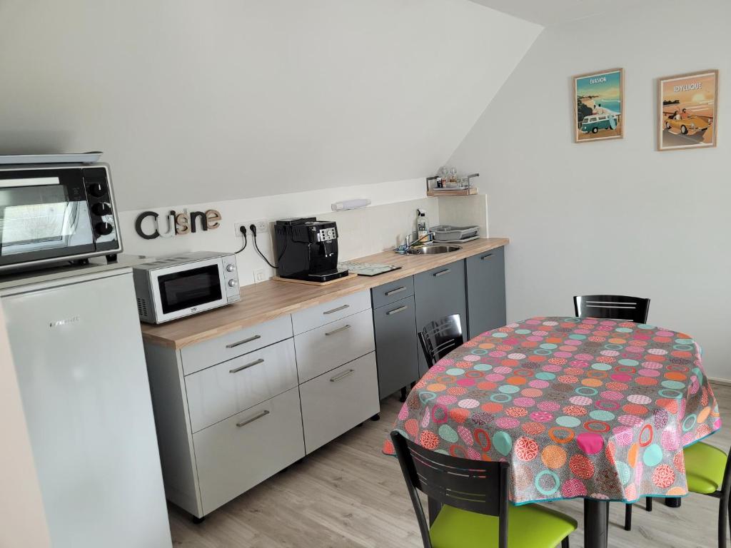 a small kitchen with a table and a microwave at Gîte Évasion idyllique à l&#39;étage près zoo-chateaux in Faverolles-sur-Cher