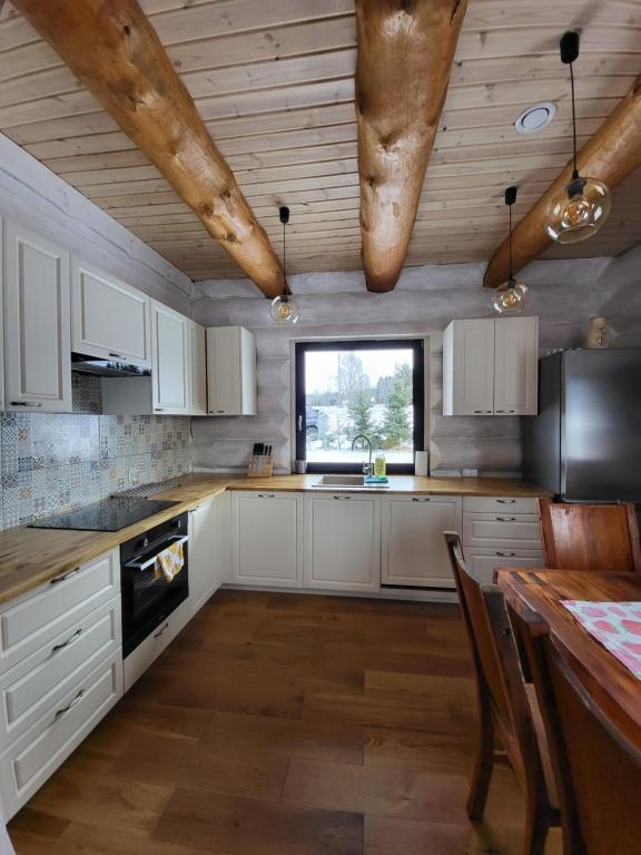 Komfortowy dom z bali koło Zieleńca z widokiem na góry في Lasowka: مطبخ بدولاب بيضاء وسقف خشبي