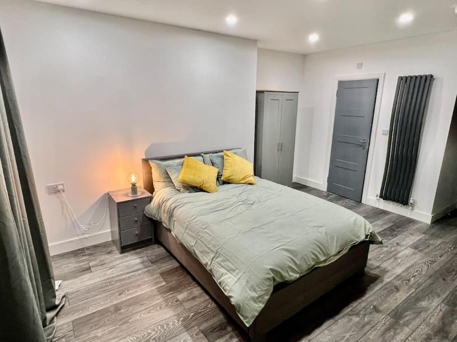 a bedroom with a bed with yellow pillows on it at cozy studio in Raynes Park House in Raynes Park