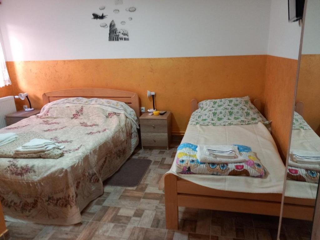 a bedroom with two beds and a night stand and a bedskirts at Sobe Viktorija in Veliko Gradište