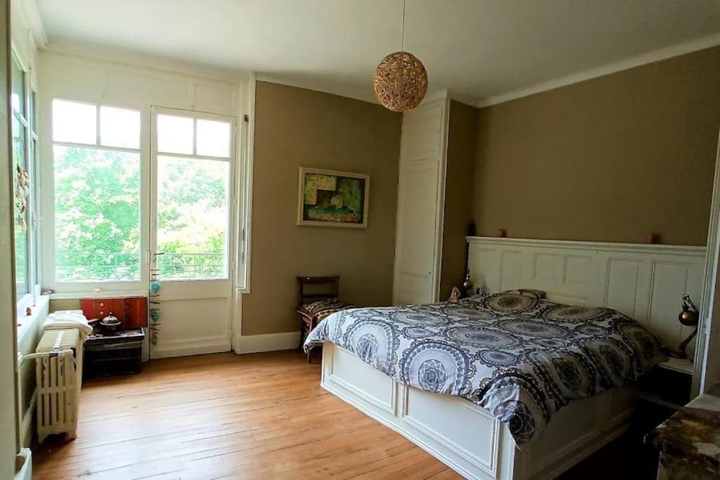 a bedroom with a bed and two windows at Maison de maître parc privé proche Crest et Drôme. in Crest