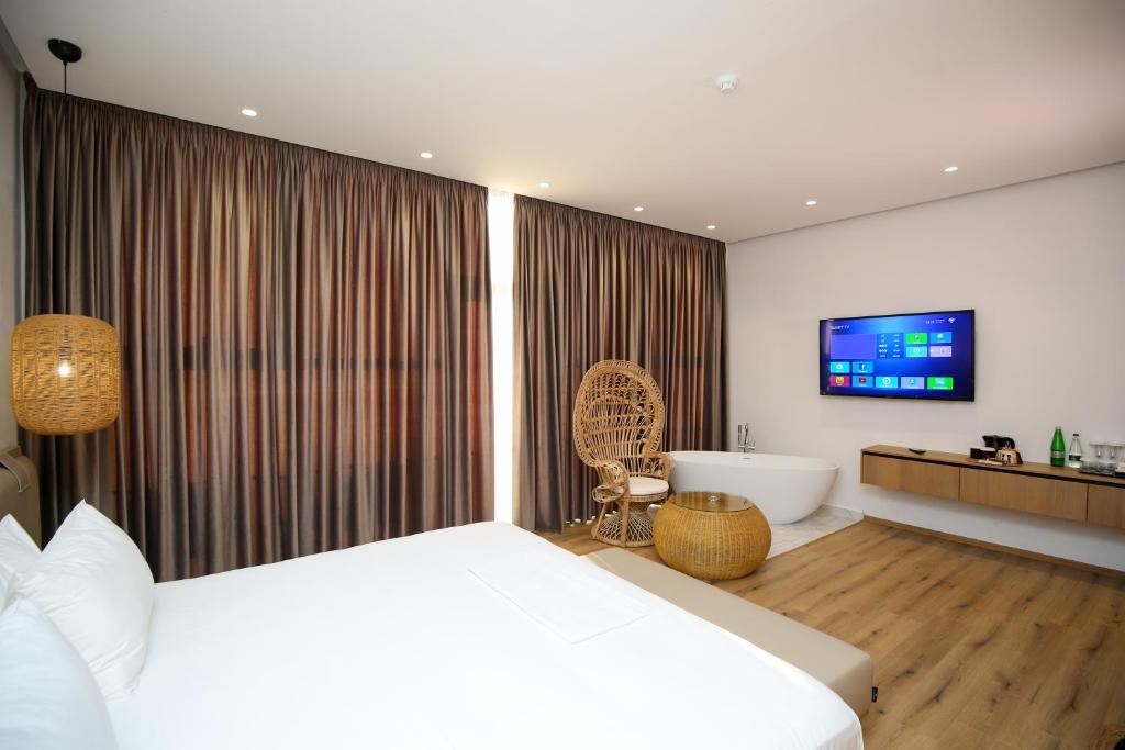 ein Schlafzimmer mit einem Bett, einer Badewanne und einem TV in der Unterkunft Oricon Coast Luxury Resort in Orikum