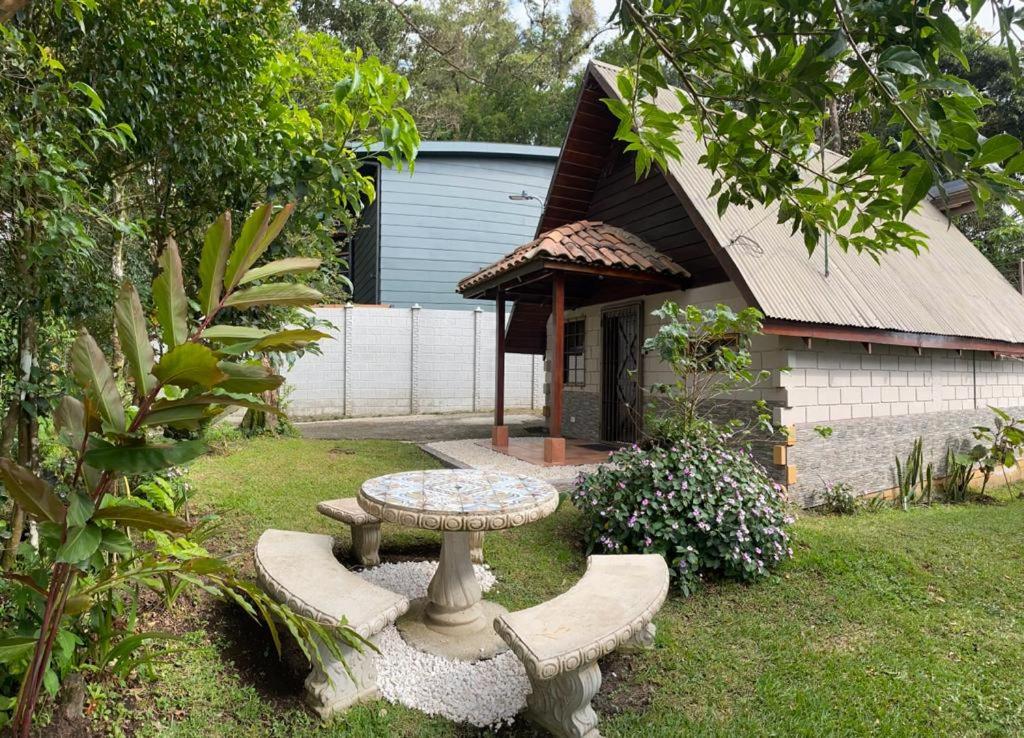 a garden with a table and bench in front of a house at Cabaña de Montaña Flaki's in Monteverde Costa Rica