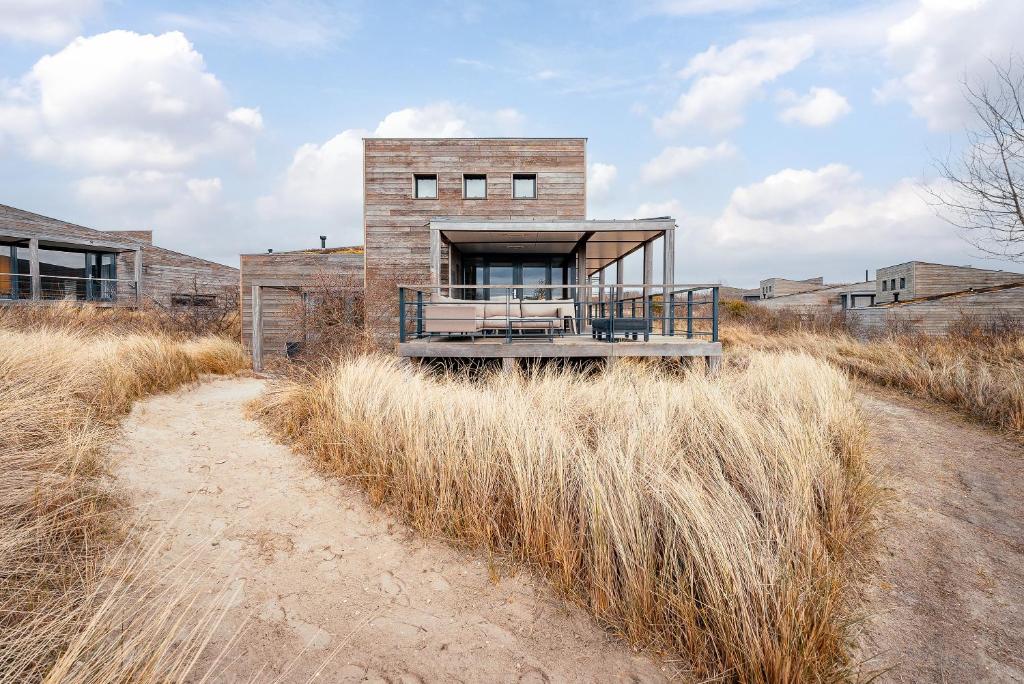 a brick house on top of a field of tall grass at Dune & Lakeview Villa 6p - Luxe, Lounge & Verwarmd Terras - Villa 30 in Ouddorp