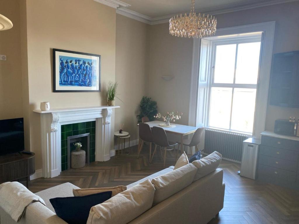 a living room with a couch and a table and a fireplace at Greystones Harbour Apartments in Na Clocha Liatha