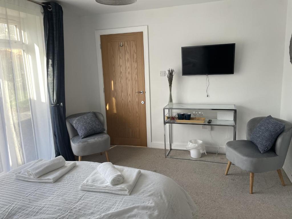 a bedroom with a bed and two chairs and a television at Porthkidney Suite, Carbis Bay, St Ives, free parking, near beach in Carbis Bay