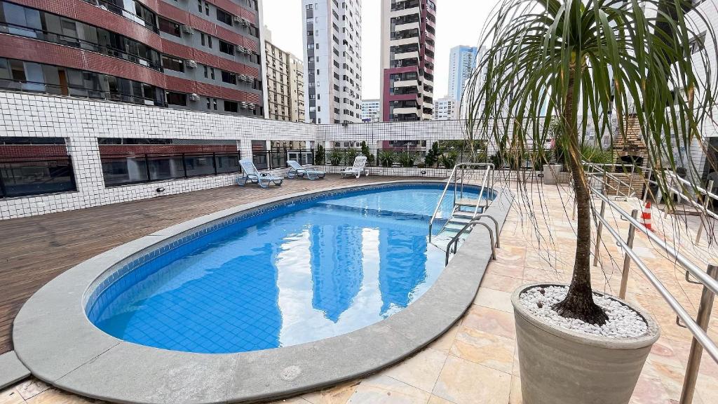 een zwembad met een palmboom naast een gebouw bij Ocean View #1401 - Apê na Praia por Carpediem in Natal