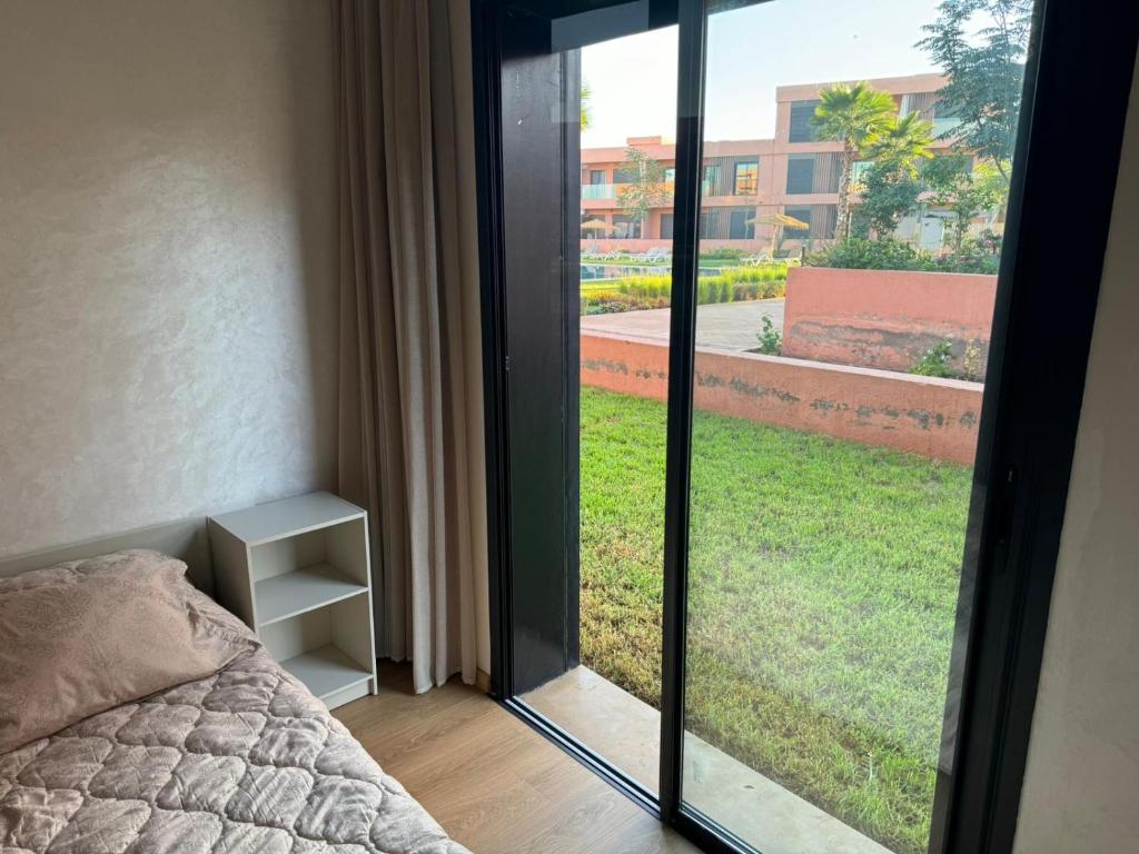 a bedroom with a bed and a sliding glass door at Appartement luxe avec piscine Marrakech in Marrakesh