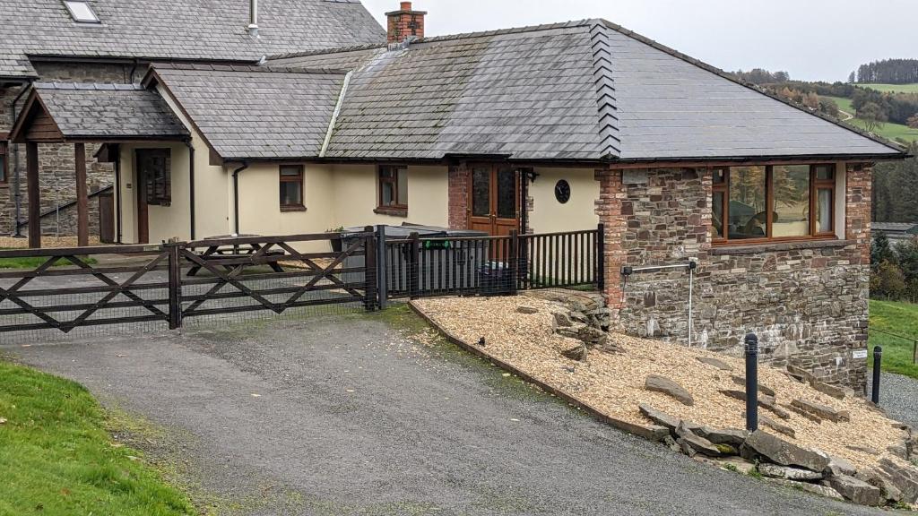 une maison avec une clôture en bois devant elle dans l'établissement Vale Farm Cottages, à Brecon