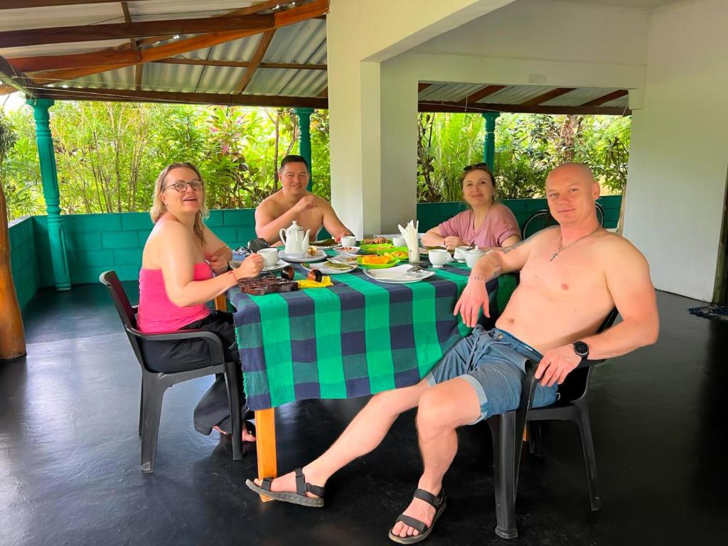 eine Gruppe von Menschen, die an einem Tisch sitzen in der Unterkunft Sigiri Sandilu Homestay in Sigiriya