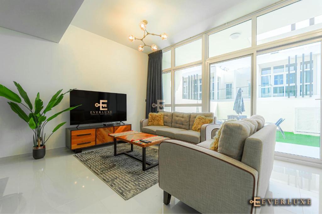 een woonkamer met een bank en een tv bij Everluxe Smart 2 Bedroom Villa In Akoya in Dubai