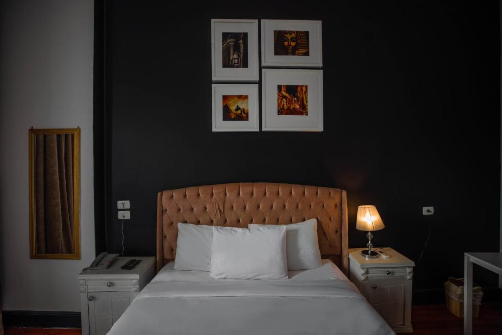 a bedroom with a white bed with two nightstands and a black wall at The Square Boutique Hotel in Cairo