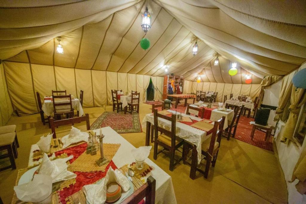 a dining room with tables and chairs in a tent at Desert Luxury Camping in Merzouga