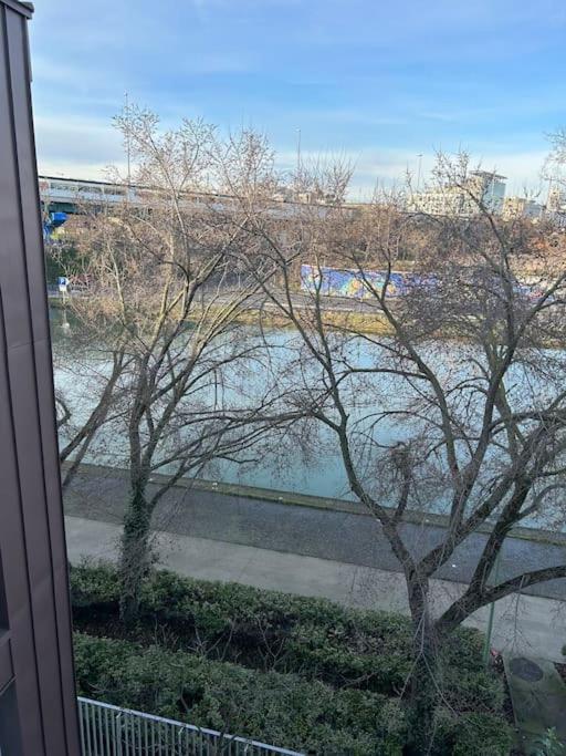 einen Blick auf den Fluss von einem Fenster mit einem Baum in der Unterkunft Vue sur canal et Stade de france in Aubervilliers