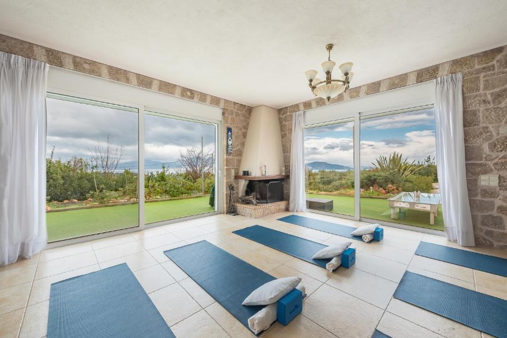 una sala de yoga con colchonetas azules y chimenea en Luxe Villa Amfiario in Attica region, pool & breathtaking views!, en Kalamos